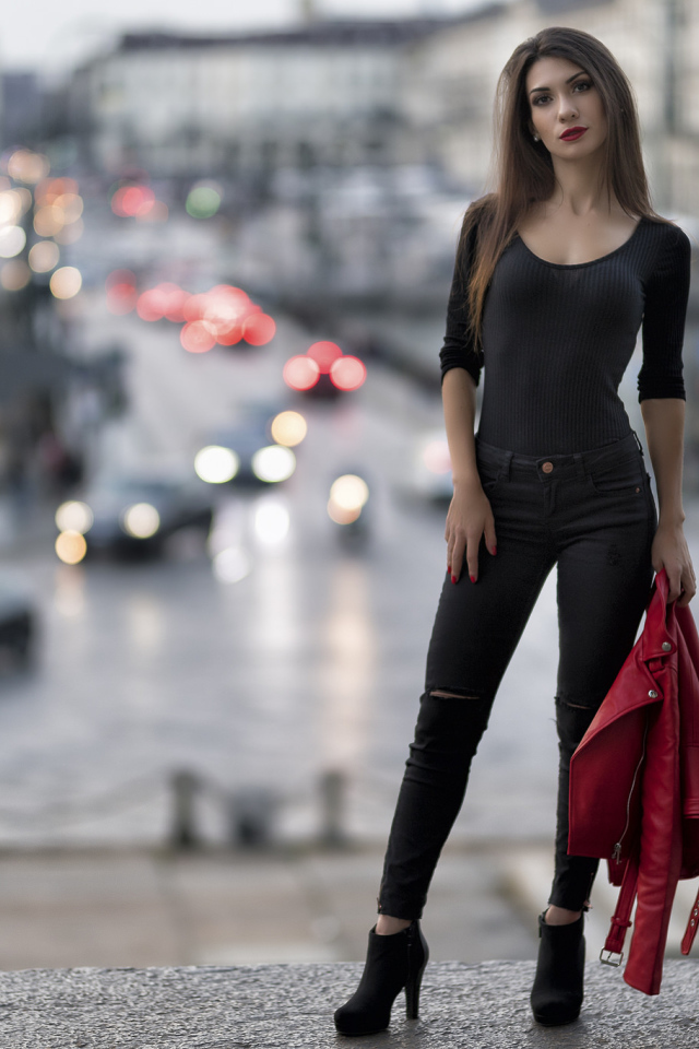 Красивая стройная девушка с красной кожаной курткой в руке