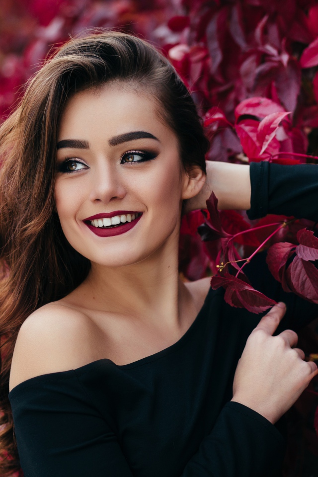 Красивая улыбающаяся длинноволосая девушка у стены с декоративным виноградом