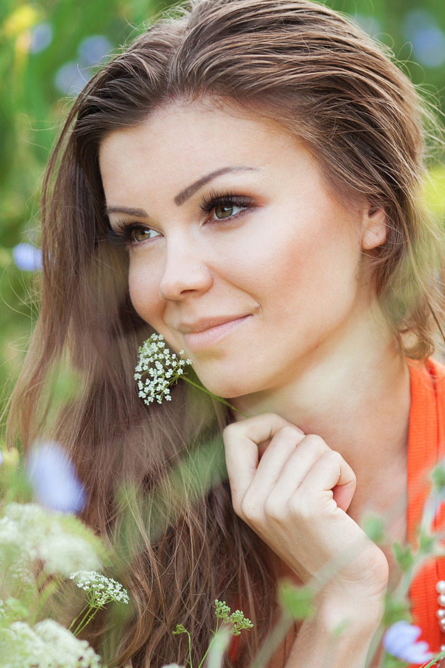 Красивая нежная девушка лежит в цветах на поле