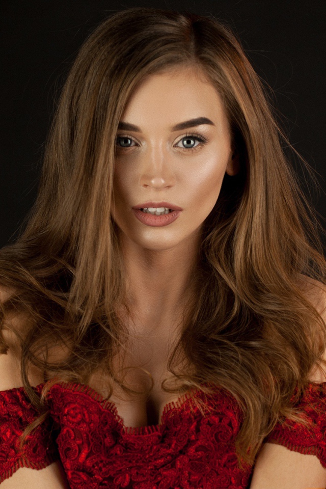 Красивая нежная длинноволосая шатенка в красном платье на черном фоне