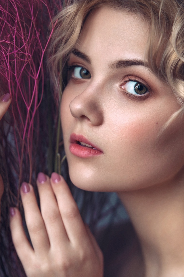 Красивая молодая блондинка с красным растением в руках