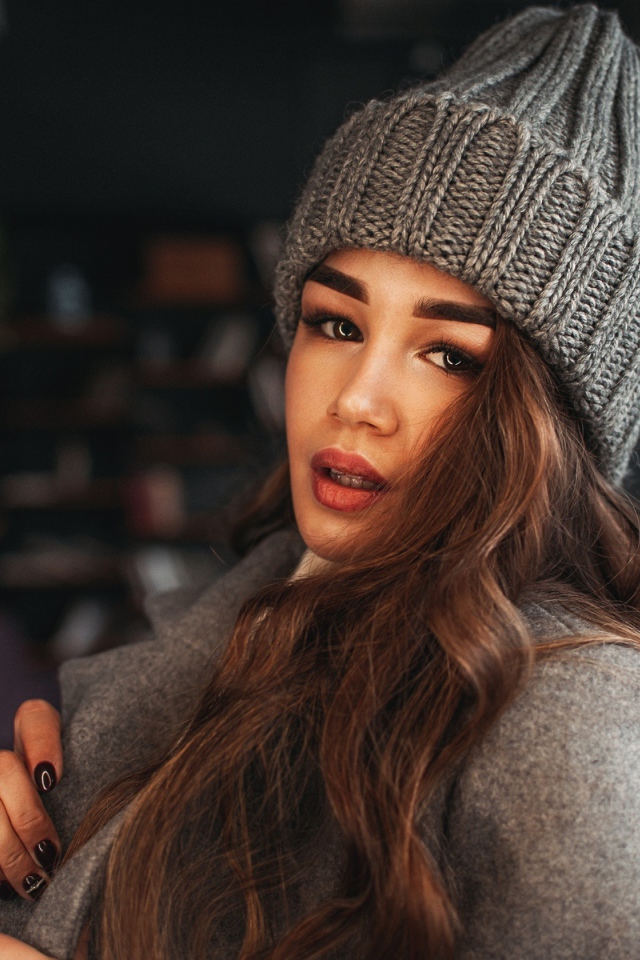 Красивая молодая девушка в пальто в вязаной шапке