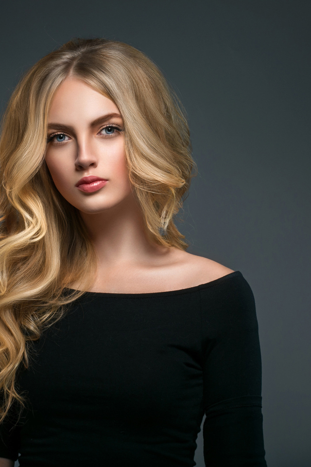 Красивая молодая девушка с длинными волосами в черном наряде на сером фоне