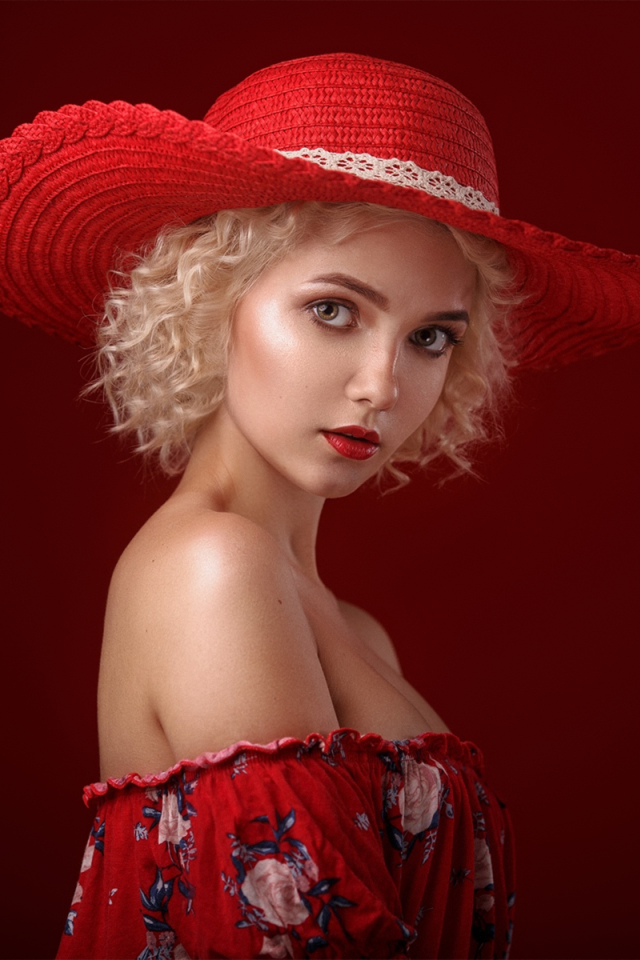 Блондинка в шляпе на красном фоне