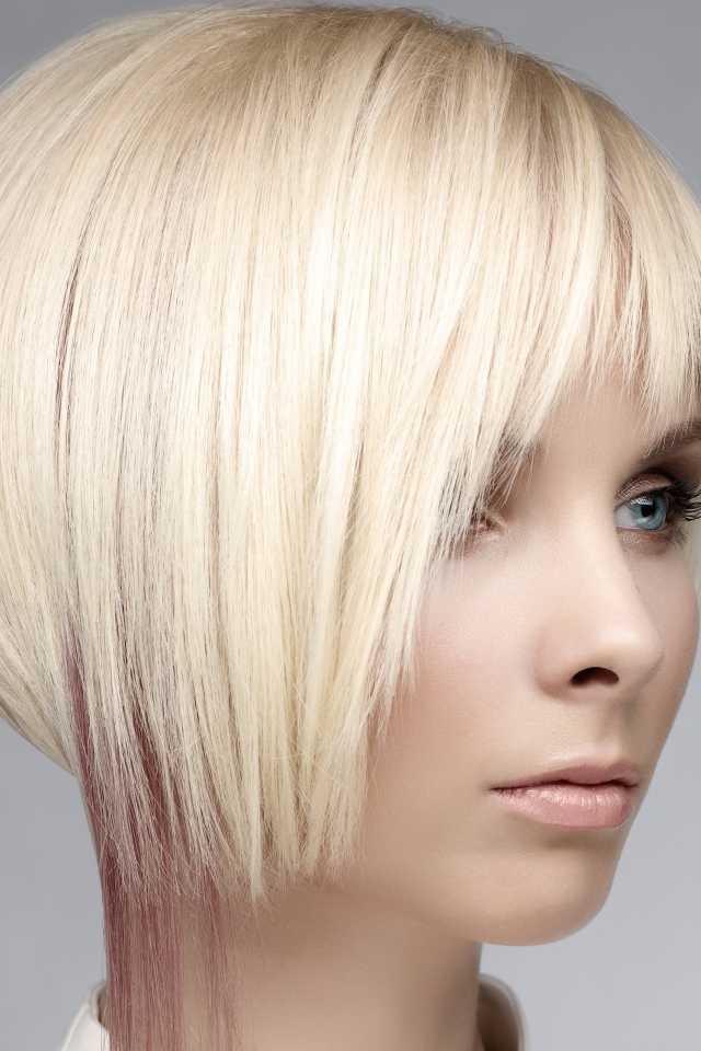 Голубоглазая девушка блондинка с короткой стрижкой на сером фоне