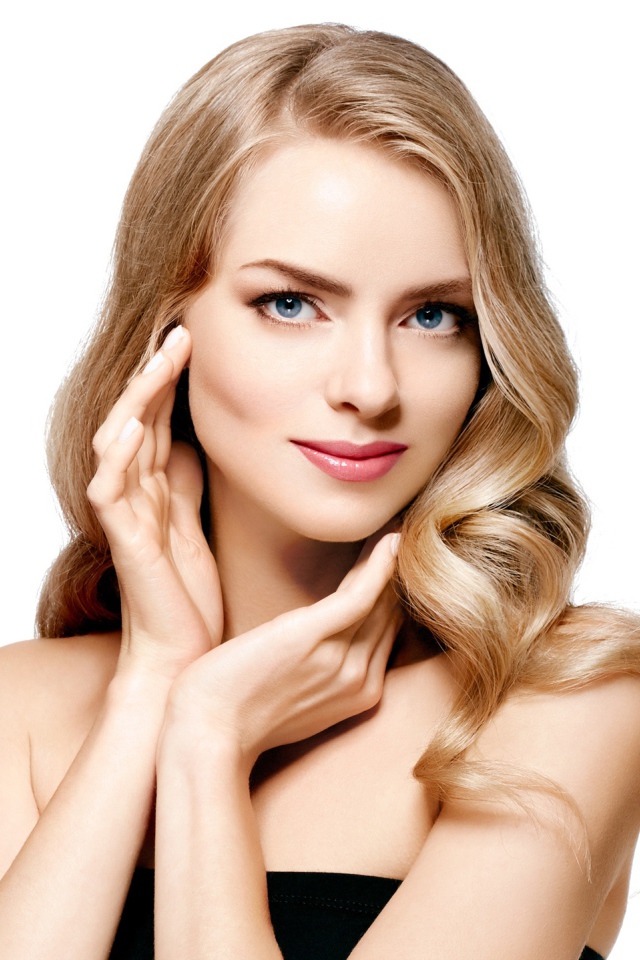 Голубоглазая блондинка с руками у лица на белом фоне