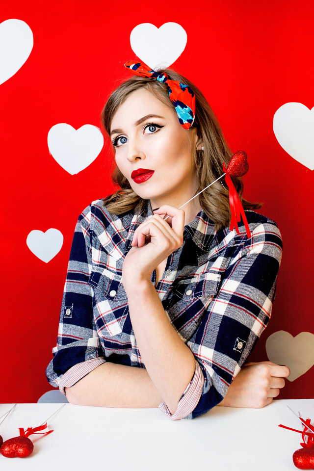 Яркая девушка за столом со сладостями на красном фоне с белыми сердечками 