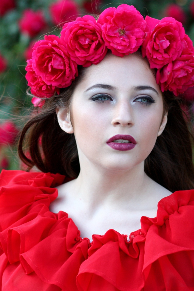 Яркая девушка в красном платье с венком из роз на голове