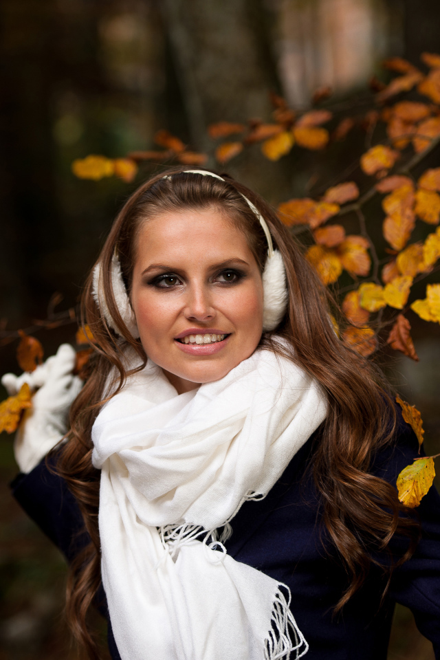 Девушка шатенка с белым шарфом стоит у дерева с желтыми листьями