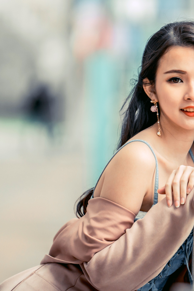 Очаровательная девушка азиатка сидит на лавке