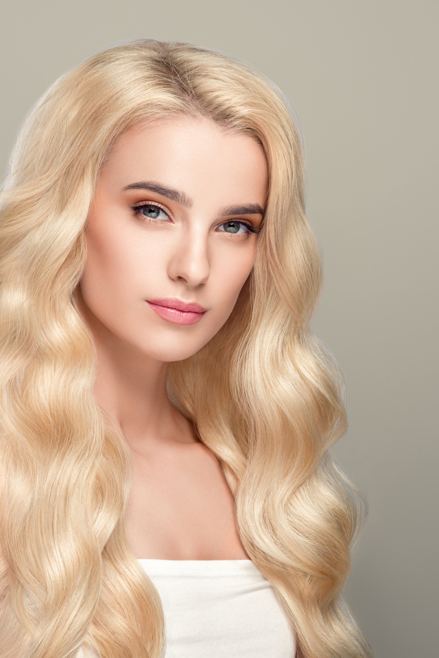 Милая длинноволосая блондинка на сером фоне