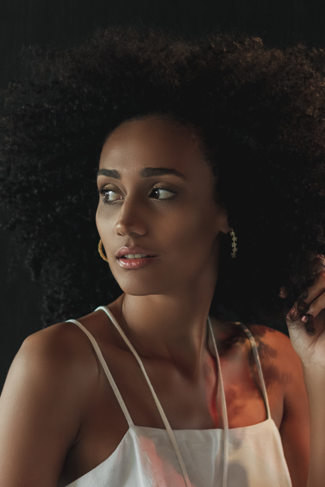 Темнокожая девушка с красивыми волосами на сером фоне