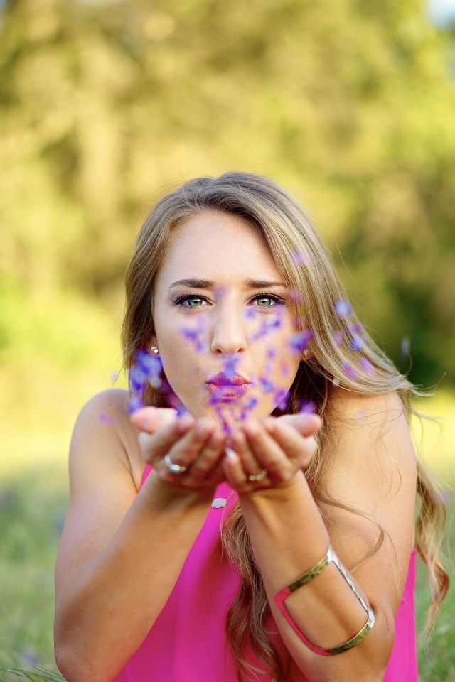 Девушка сдувает лепестки с ладоней 