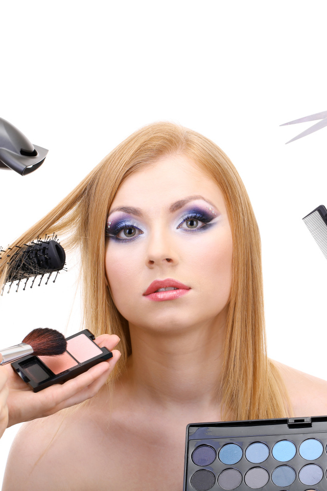 Девушке делают макияж и прическу на белом фоне