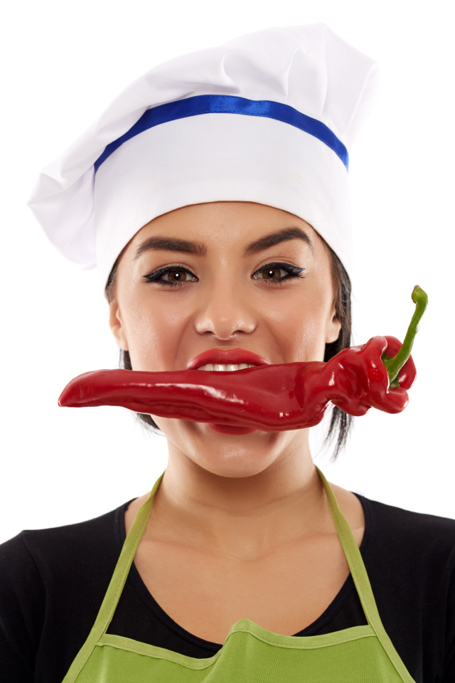 Девушка в шапке повара с красным перцем во рту на белом фоне