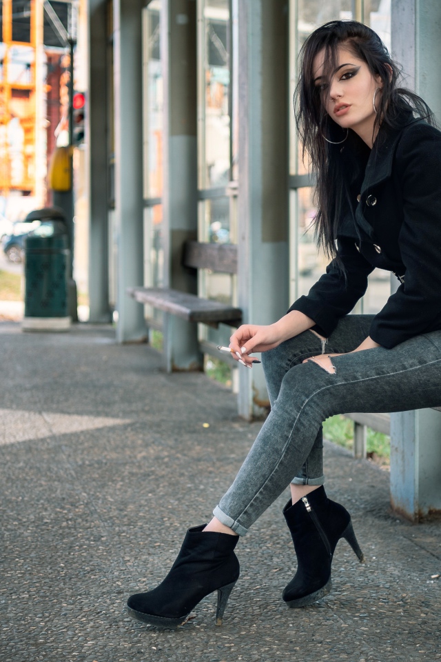 Девушка неформалка сидит на автобусной остановке