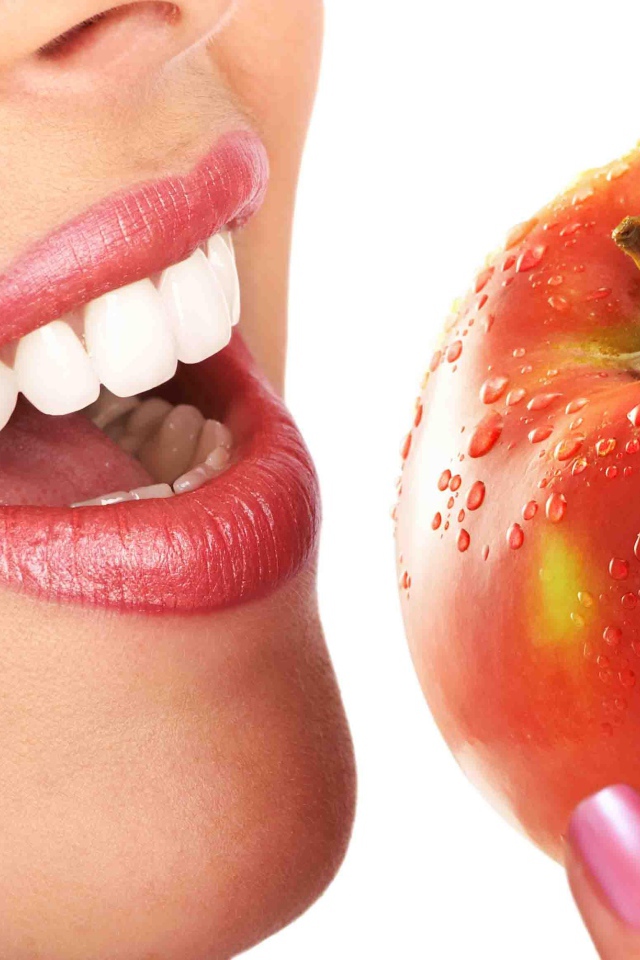 Девушка с красивыми белыми зубами кусает яблоко