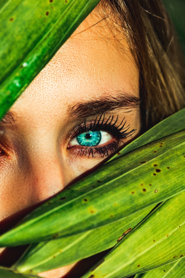 Девушка с голубыми глазами в зеленых листьях 