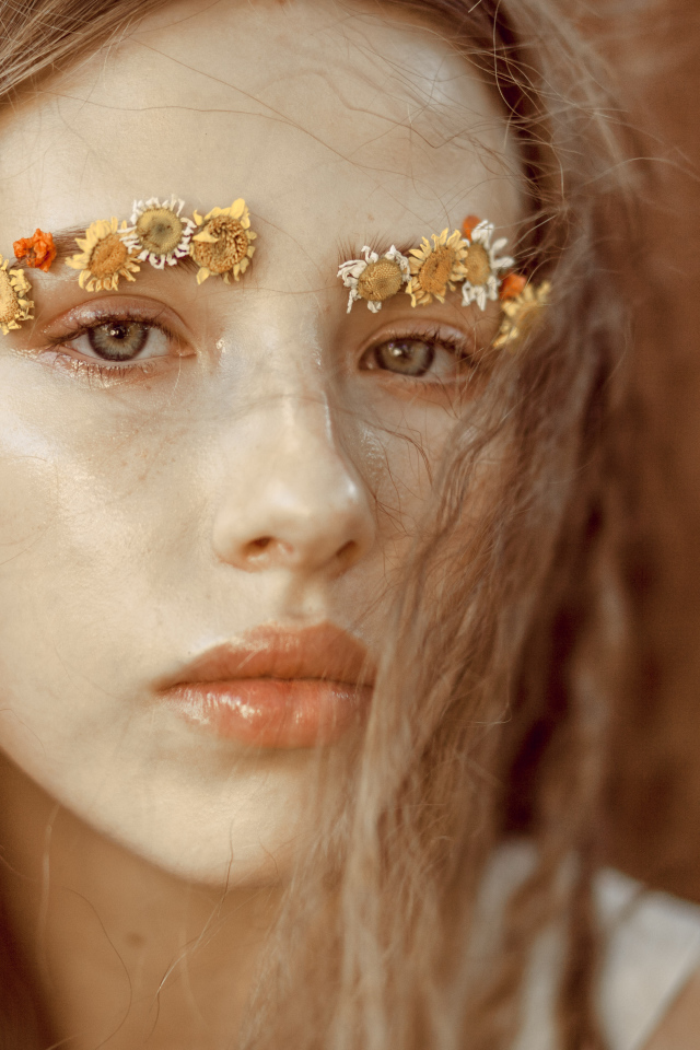 Девушка с цветами на бровях крупным планом