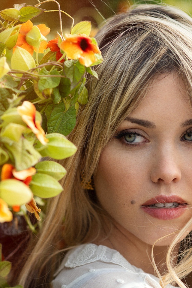 Зеленоглазая блондинка у забора с цветами 