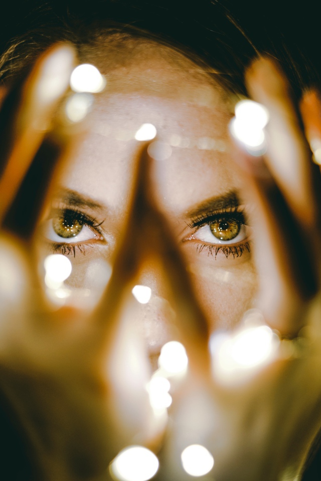 Руки с гирляндой у лица девушки