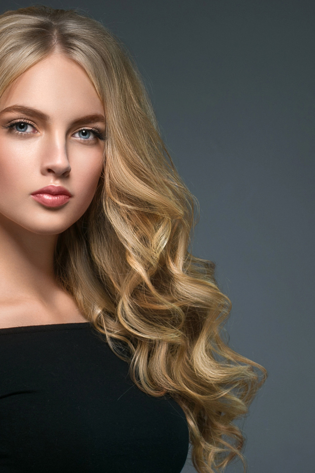 Длинноволосая блондинка с голубыми глазами на сером фоне