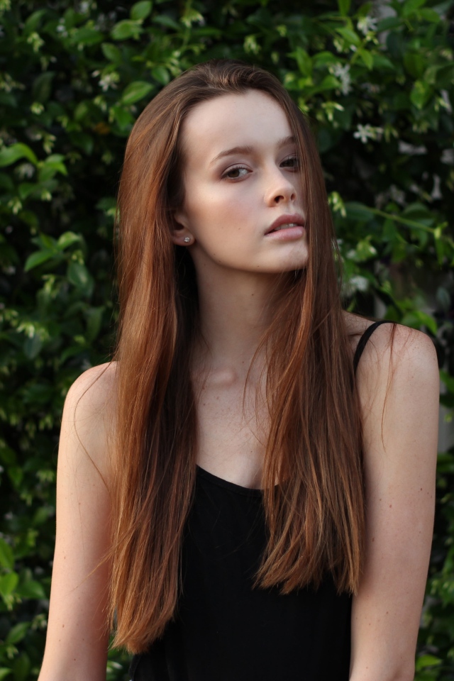 Длинноволосая шатенка на фоне зеленых зарослей