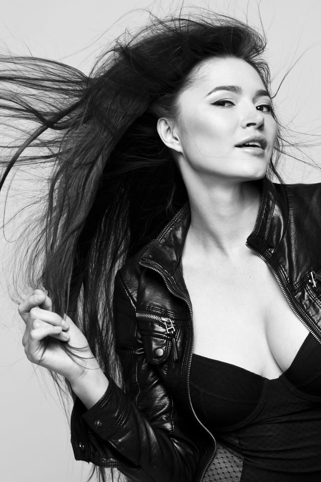 Длинноволосая брюнетка с кожаной куртке на сером фоне