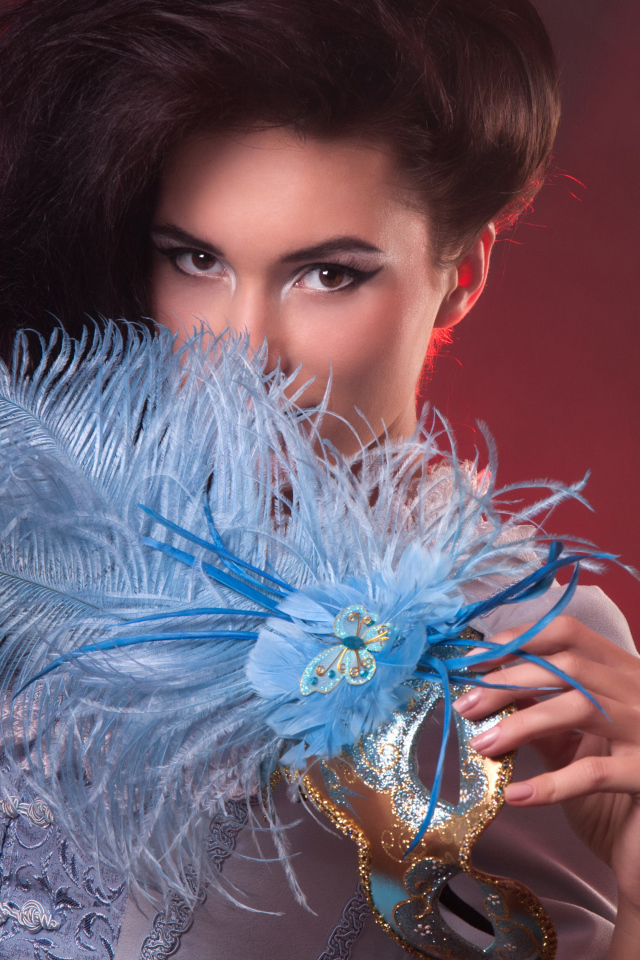 Длинноволосая девушка с маской с перьями в руке