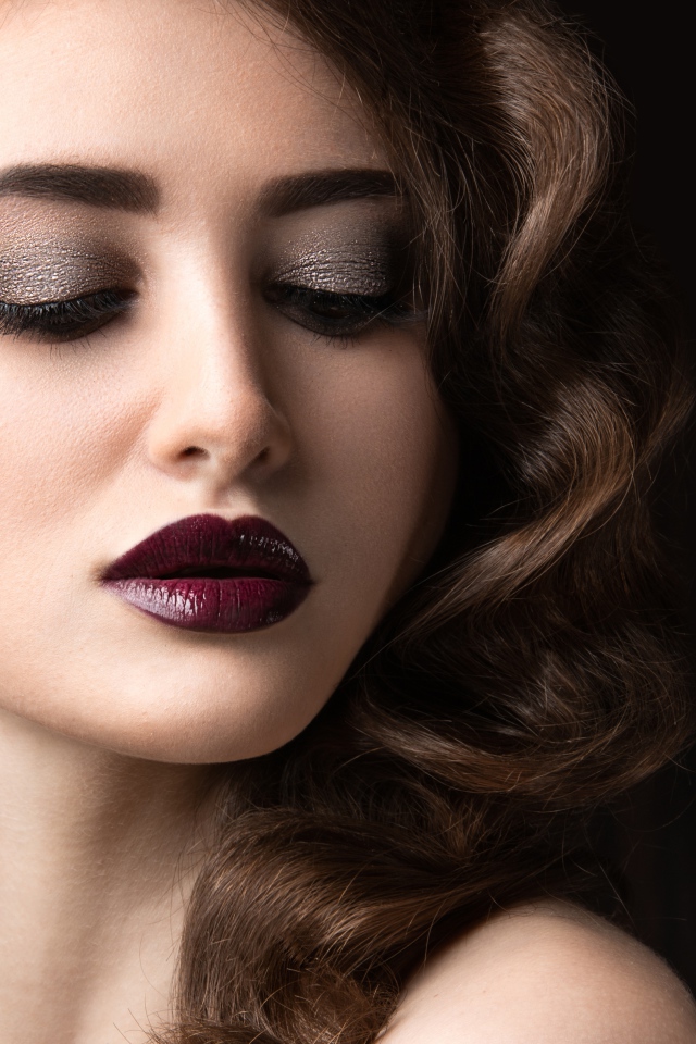 Длинноволосая девушка с ярким макияжем на черном фоне