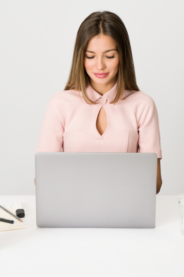 Умная девушка за ноутбуком на сером фоне