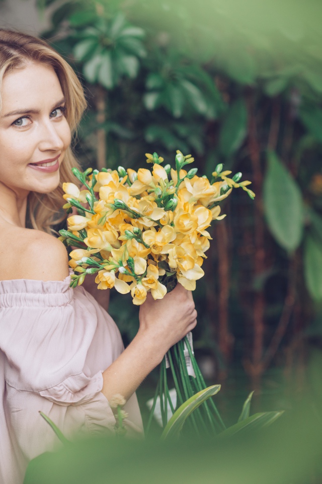 Улыбающаяся блондинка с букетом хризантем в руках