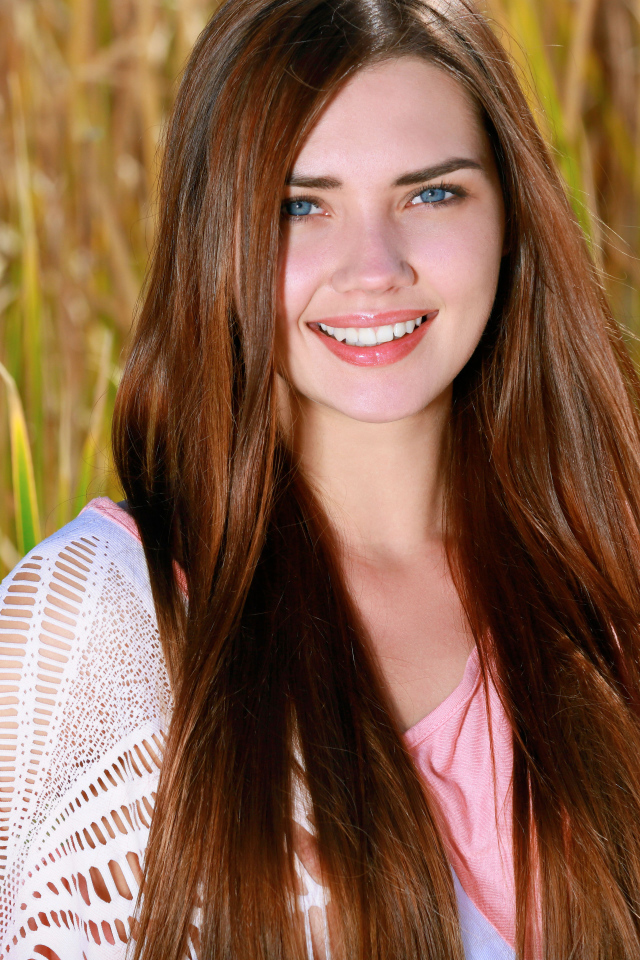 Улыбающаяся голубоглазая шатенка на поле