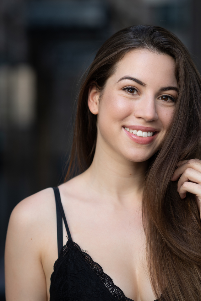 Улыбающаяся девушка держит длинные волосы