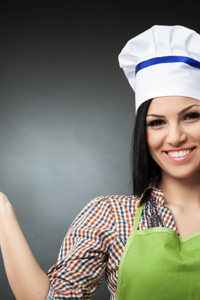 Улыбающаяся девушка в поварском колпаке на сером фоне