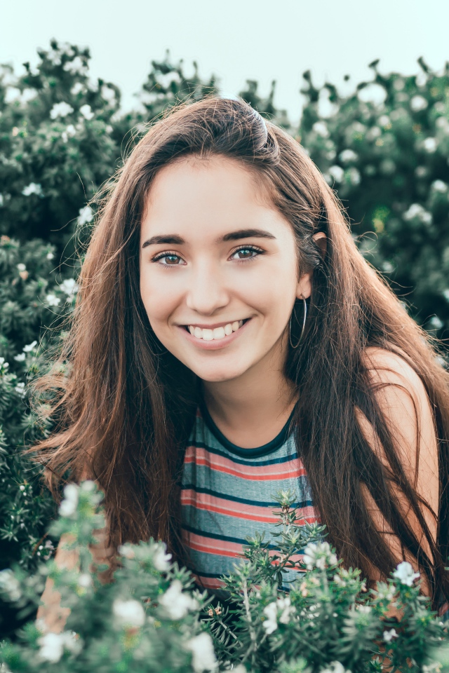 Улыбающаяся девушка сидит в зеленых зарослях 