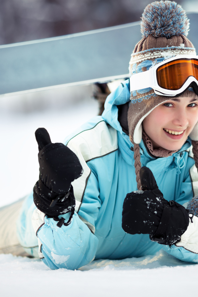 Улыбающаяся девушка сноубордистка на снегу зимой