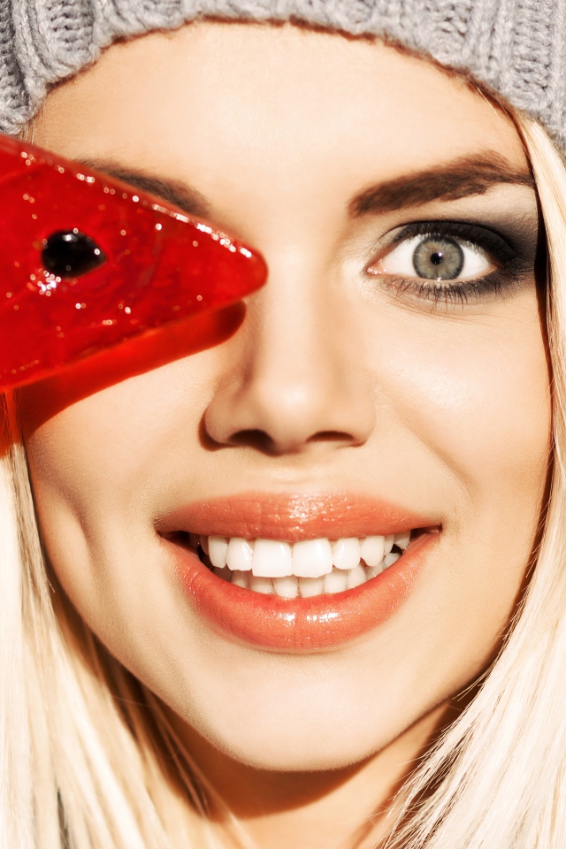 Улыбающаяся девушка с леденцом в руке крупным планом