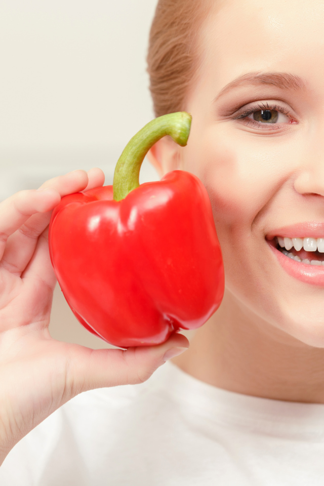 Улыбающаяся девушка с красным сладким перцем в руке