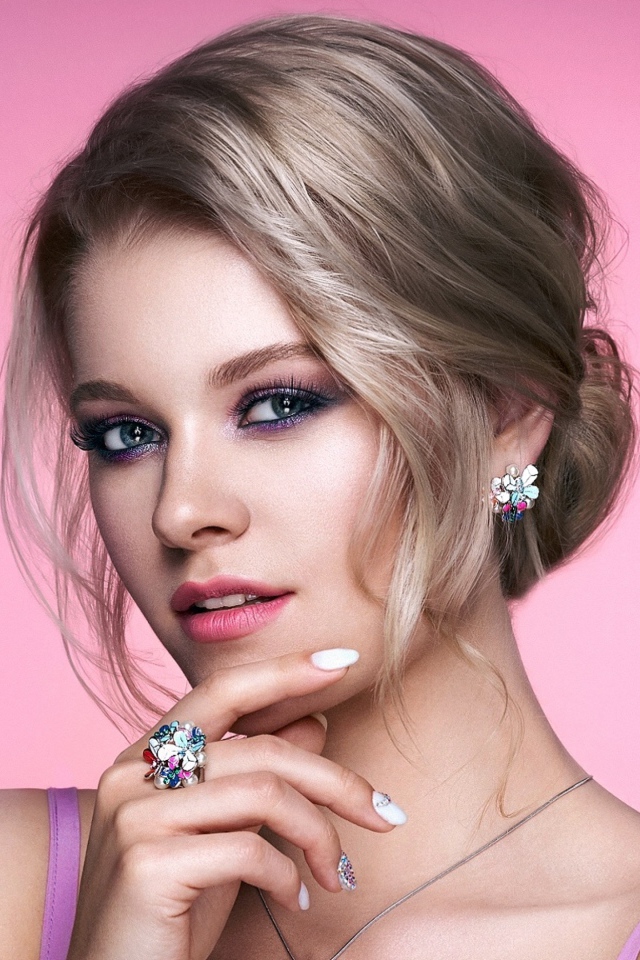 Стильная блондинка с прической на розовом фоне