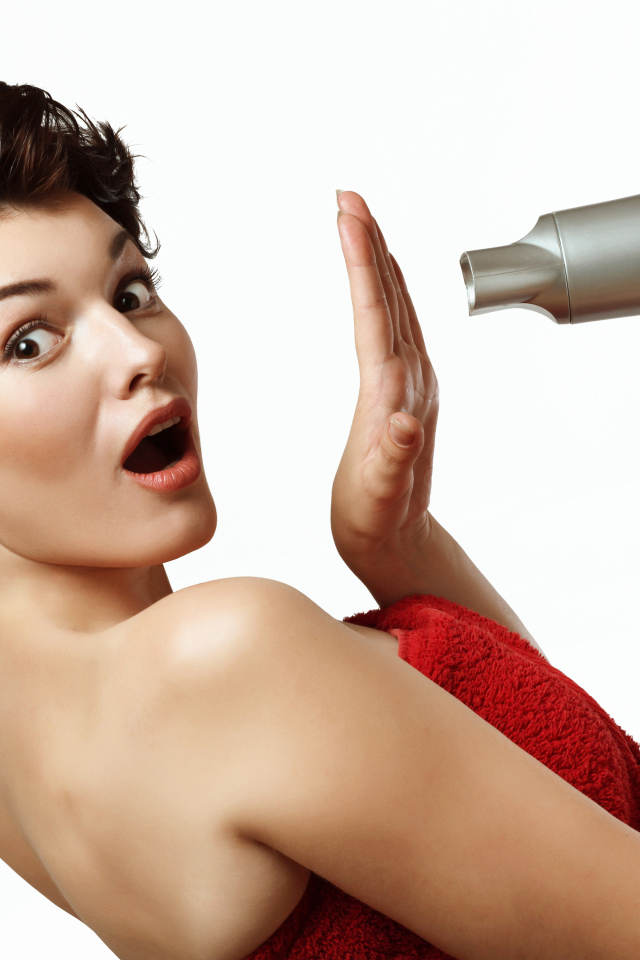 Удивленная девушка с феном в руках на белом фоне