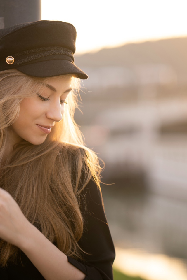 Нежная девушка в черной кепке в лучах солнца