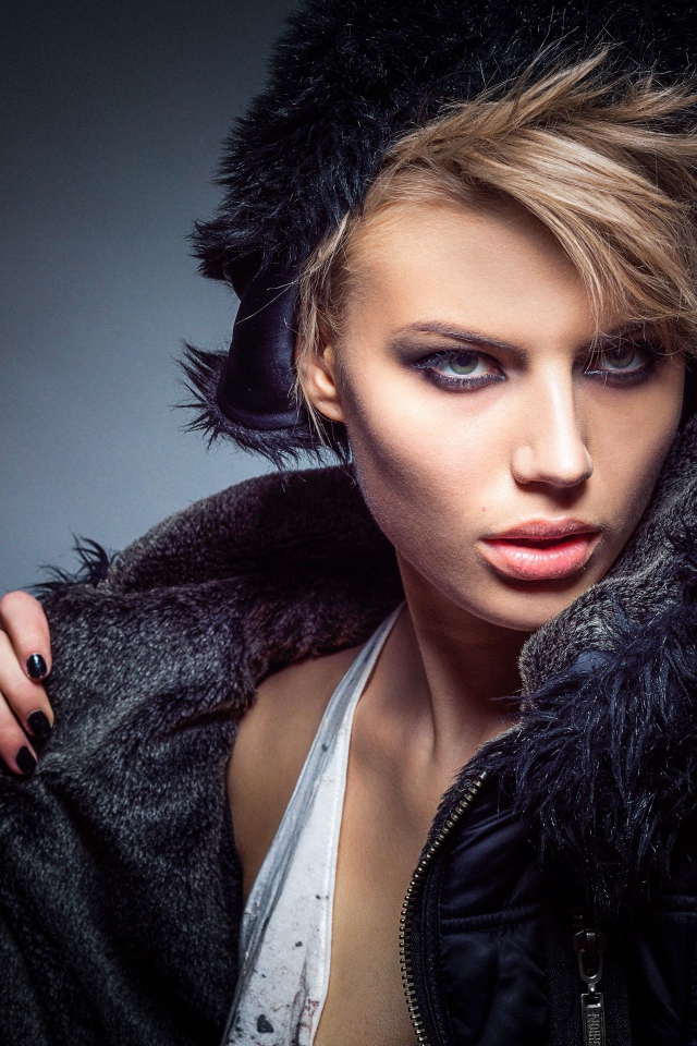 Девушка в теплой жилетке и шапке на сером фоне