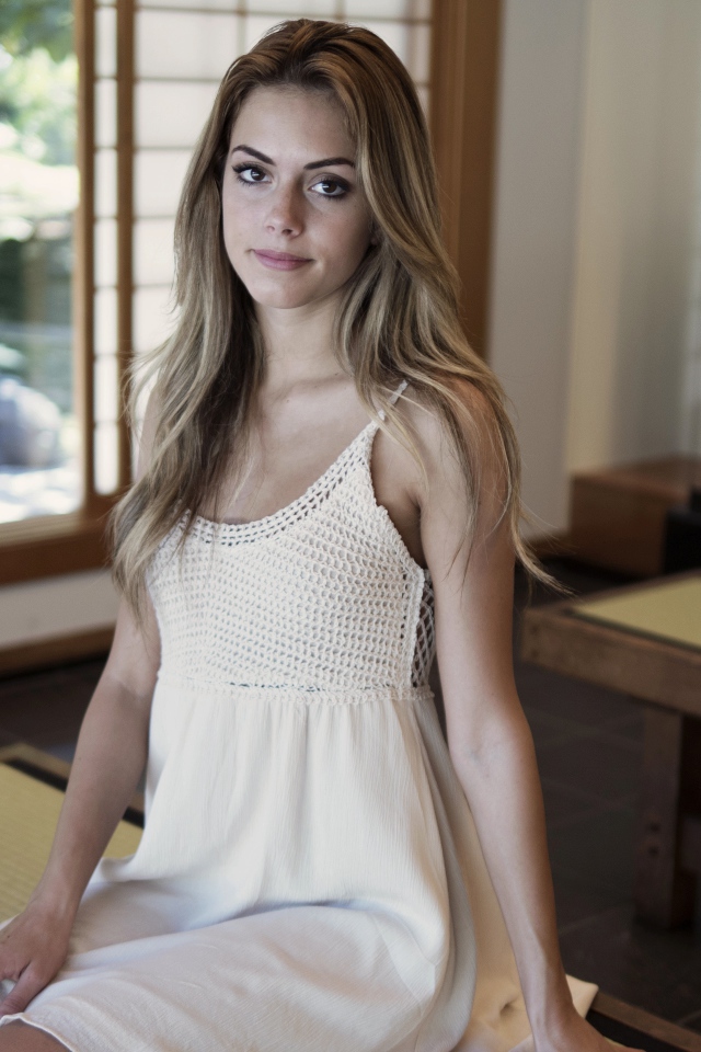 Девушка в белом сарафане сидит на лавке 