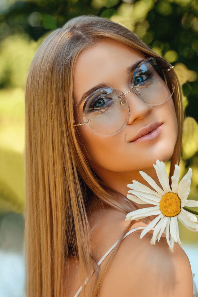 Девушка в очках с ромашкой в руке 