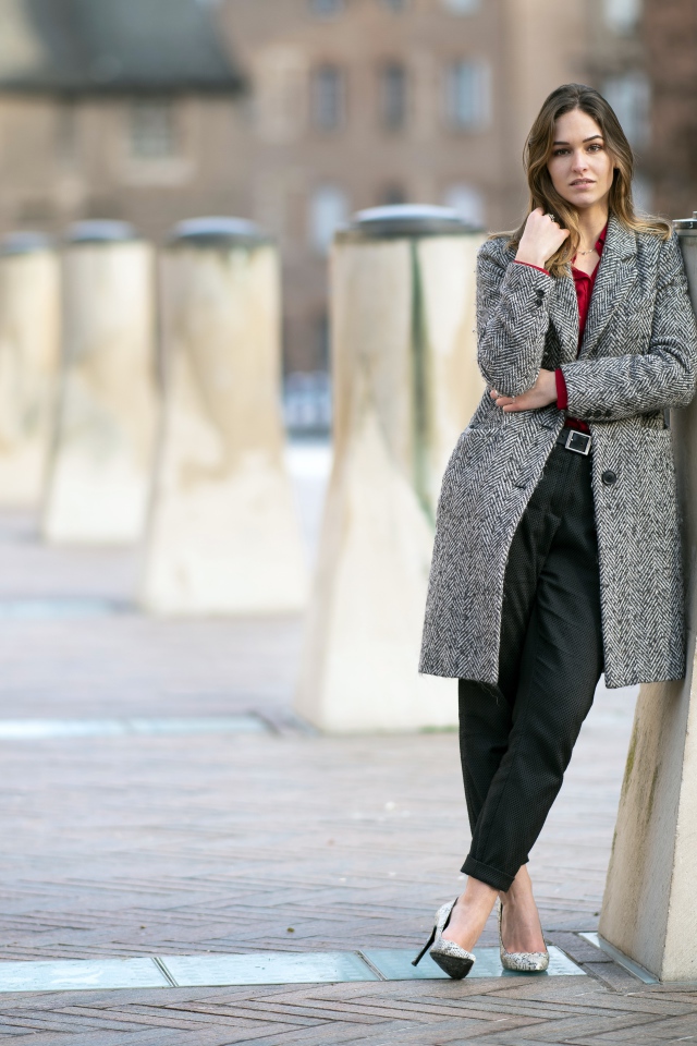 Девушка стоит в сером пальто 