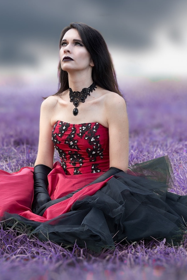 Девушка с макияжем в красивом платье сидит на траве