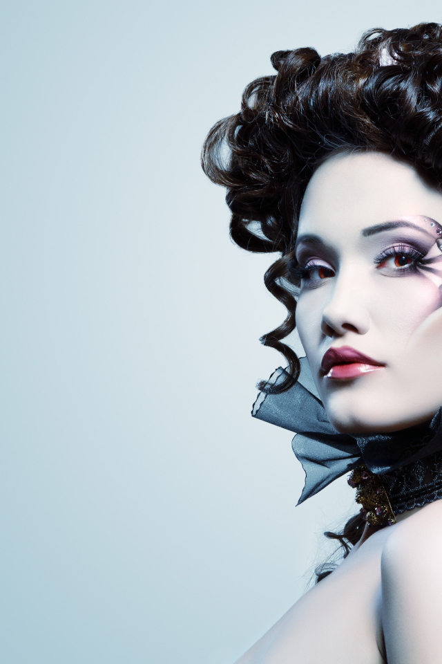 Девушка с необыной прической и макияжем на сером фоне