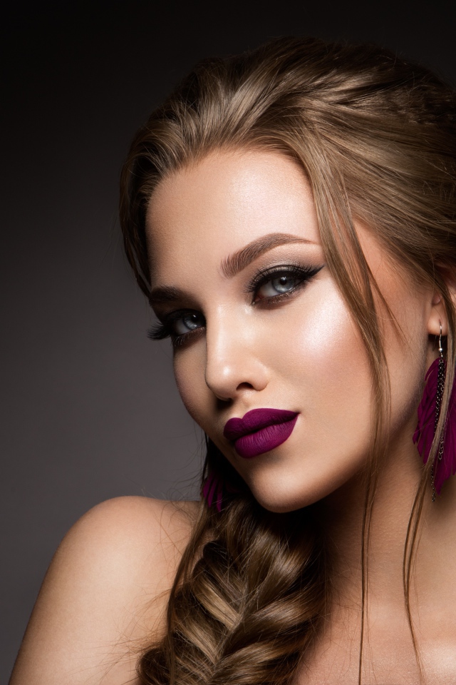 Девушка с ярким макияжем и косой на сером фоне