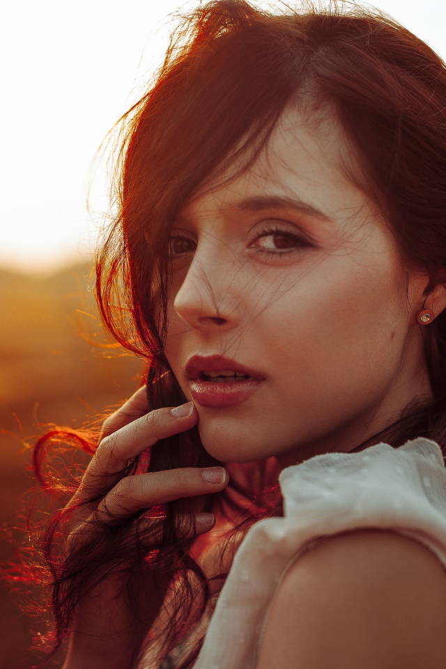 Ветер развивает волосы молодой девушки 